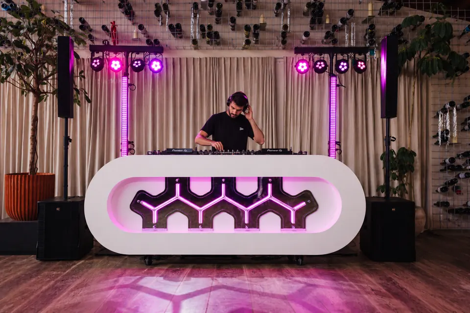 DJ achter de witte DJ-booth met geluid en licht
