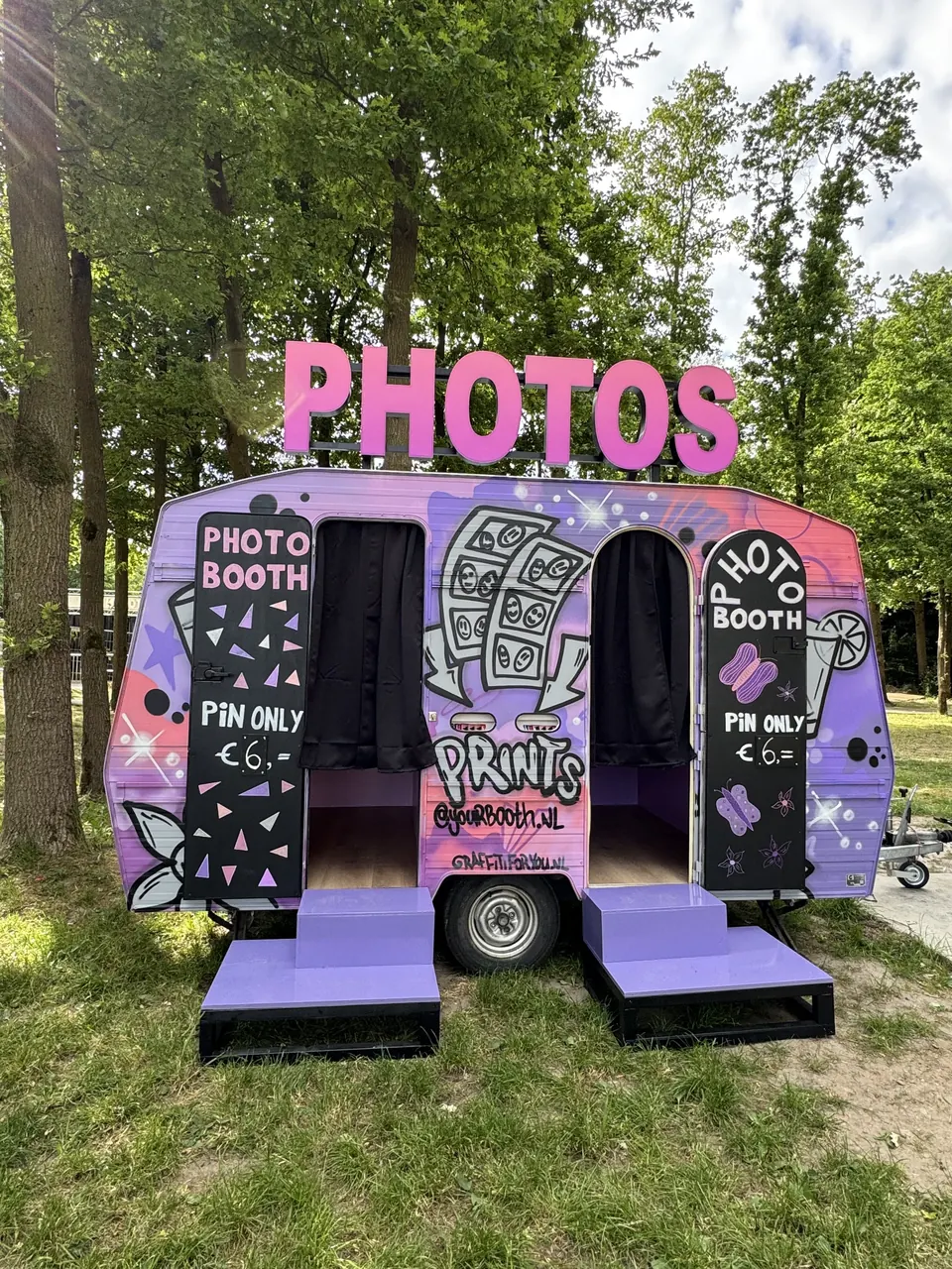 Paarse caravan photobooth op een festivalterrein